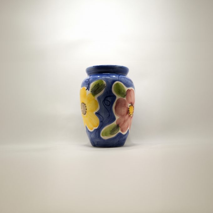 A blue flower vase with yellow, red and blue flowers