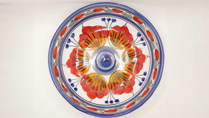 a red poppy like flower on a blue and white bowl made in italy