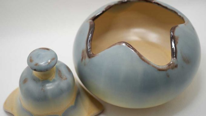 A blue and cream pot with a puzzle like lid that fits to the base