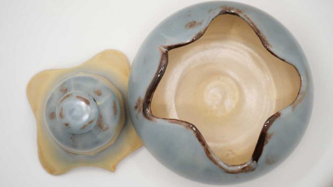 A blue and cream pot with a puzzle like lid that fits to the base
